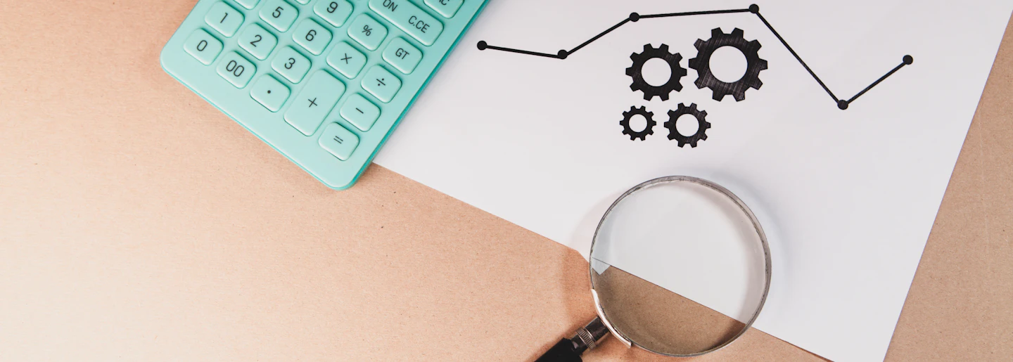 A magnifying glass and calculator resting on a printed chart