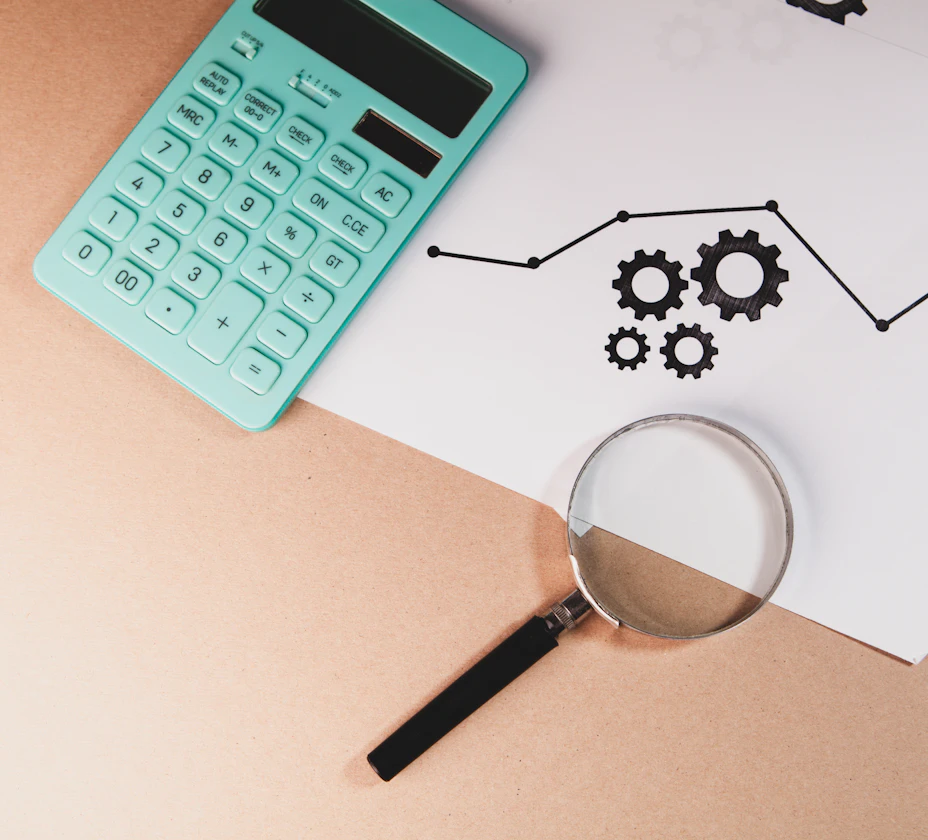 A magnifying glass and calculator resting on a printed chart
