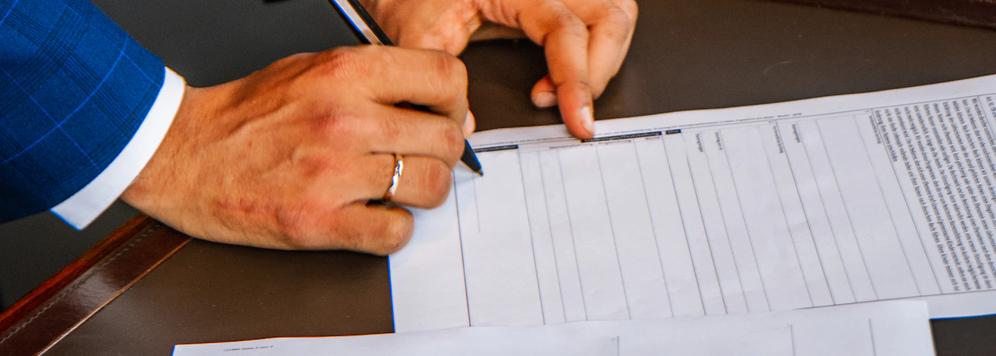A person in a suit filling in an official printed form with a pen