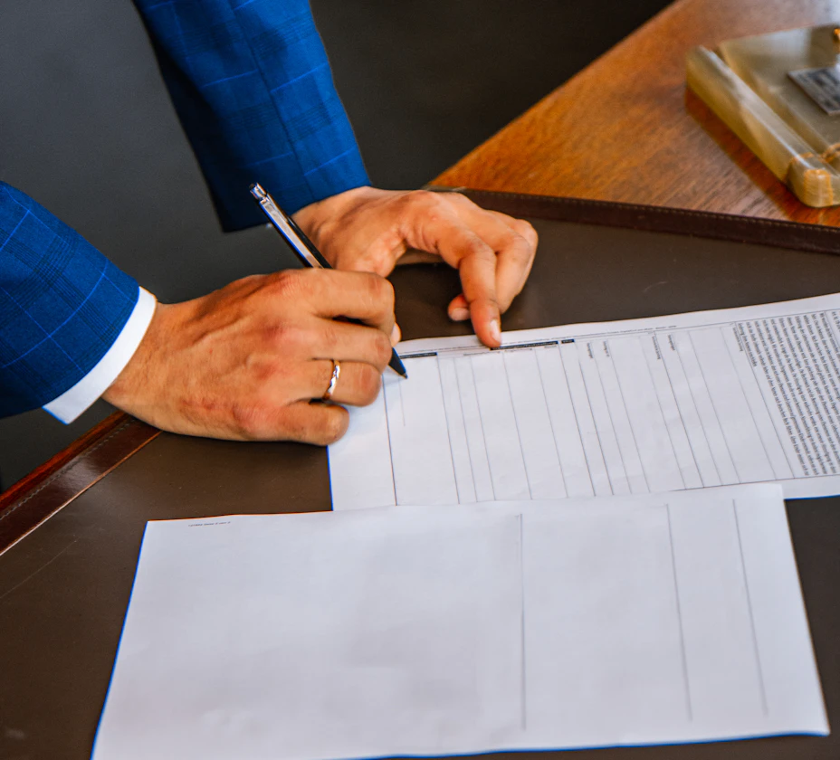 A person in a suit filling in an official printed form with a pen