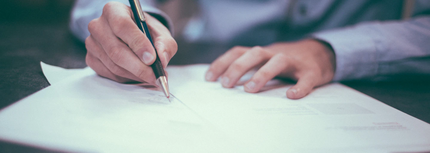 Close-up of a person signing a printed document with a pen