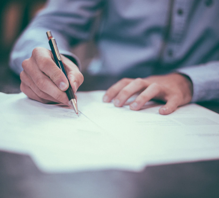 Close-up of a person signing a printed document with a pen
