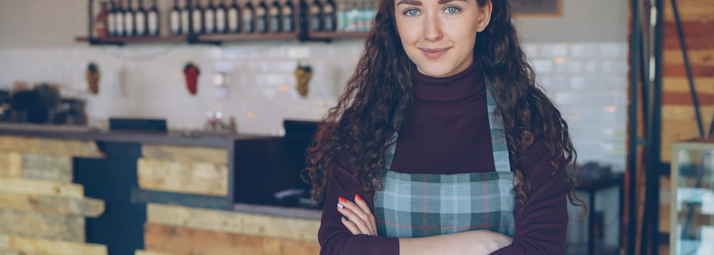 Small business owner smiling behind the counter of her shop