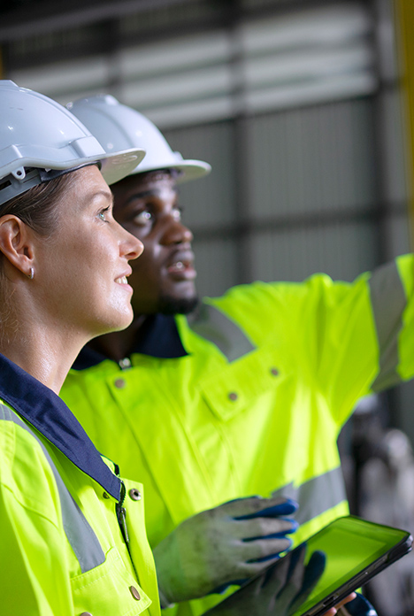 Two Engineers In Hard Hats And Hi Vis Inspecting An Industrial Site